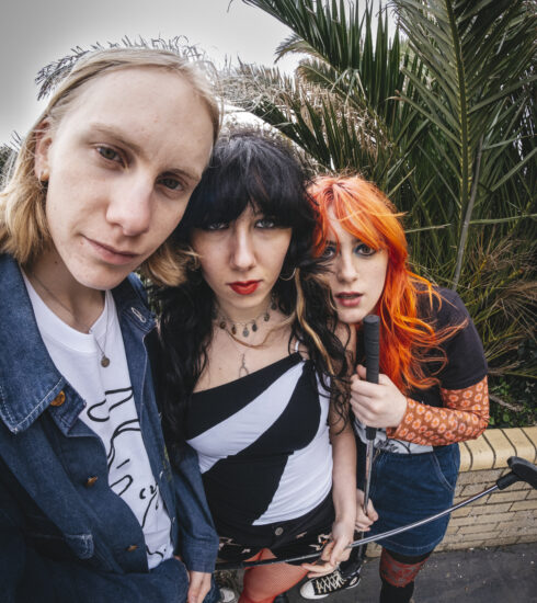 3 members of the band HotWax standing in front of a palm tree